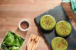 Raw green plant based meatless spinach burgers with spices on a stone plate